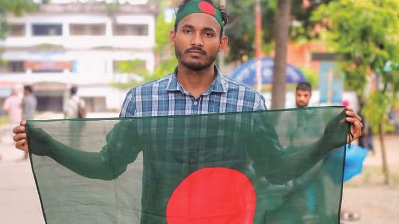 ১৪ জুলাই ২০২৪ তারিখে কোটা সংস্কারের দাবিতে রংপুর শহরের টাউন হলের সামনে পতাকা হাতে নিয়ে দাঁড়ায় আবু সাঈদ