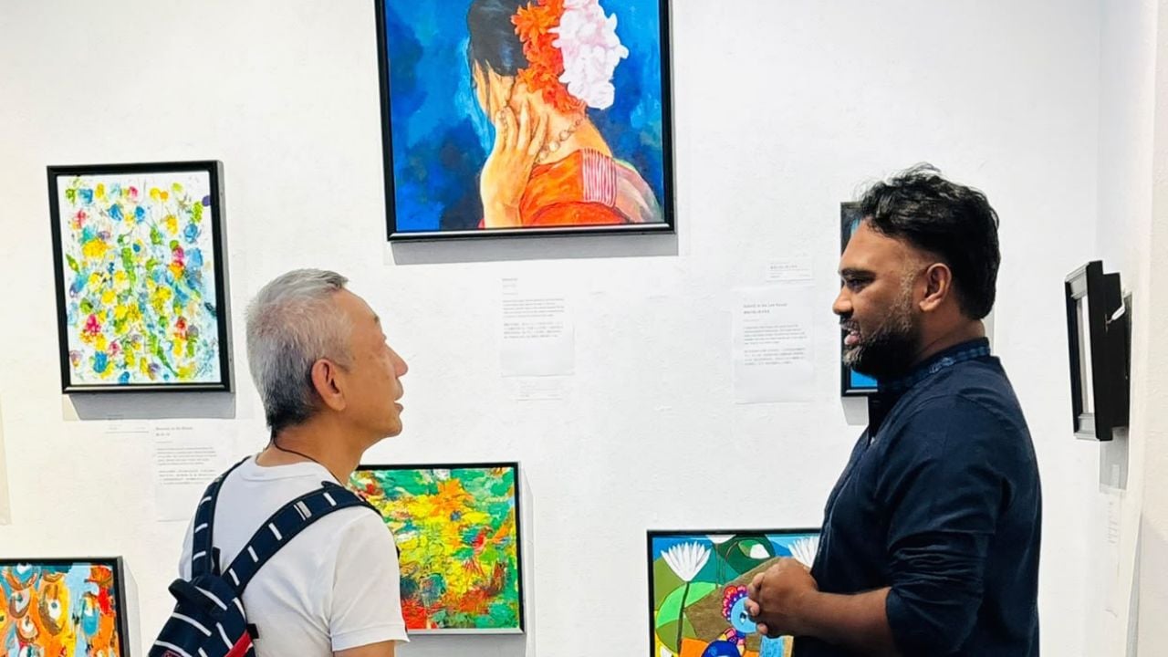 প্রদর্শনীতে আসা এক দর্শকের সঙ্গে কথা বলছেন চিত্রশিল্পী কামরুল হাসান লিপু