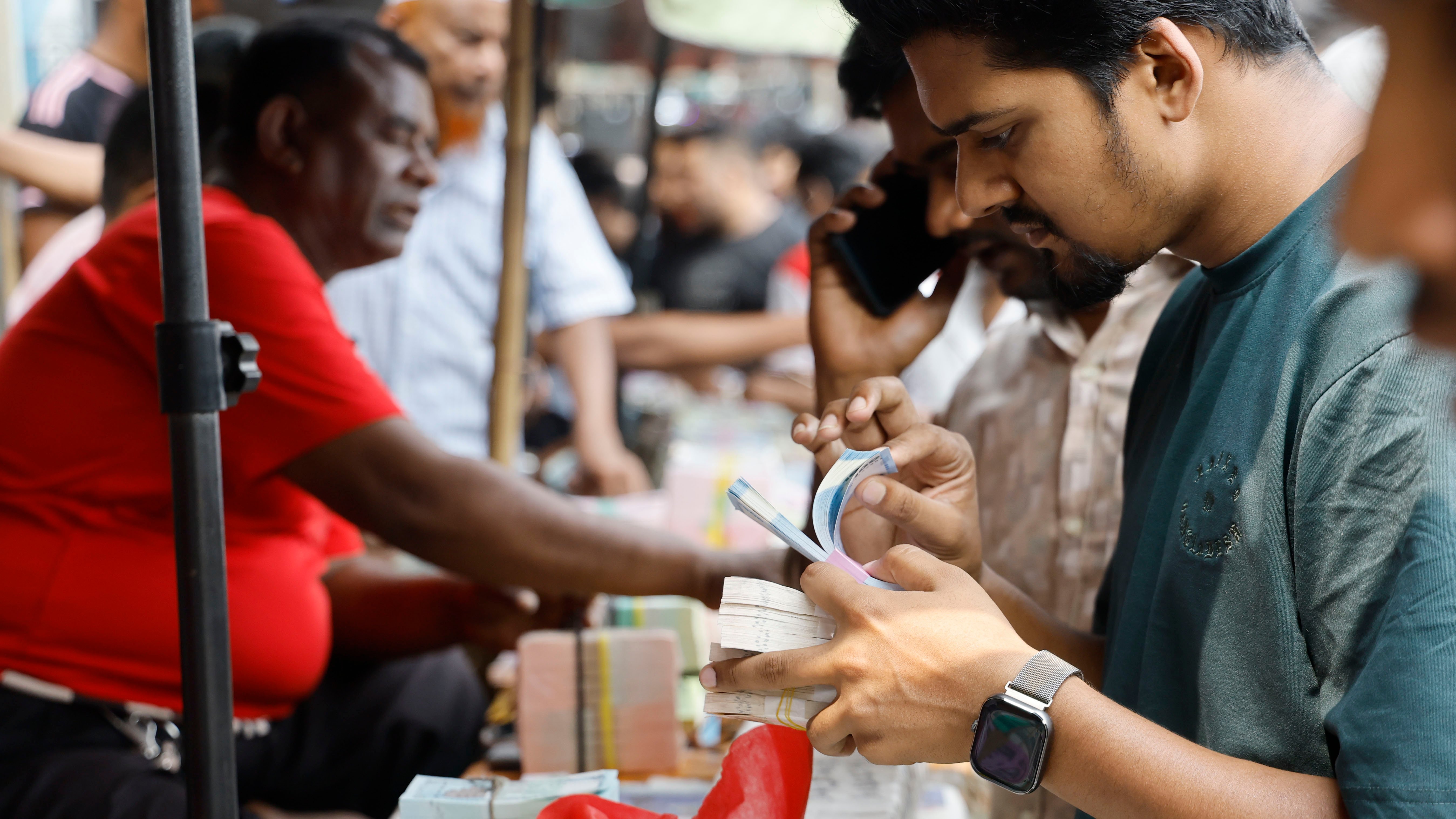 টাকা কেনার পর পরখ করে দেখছেন এক ক্রেতা