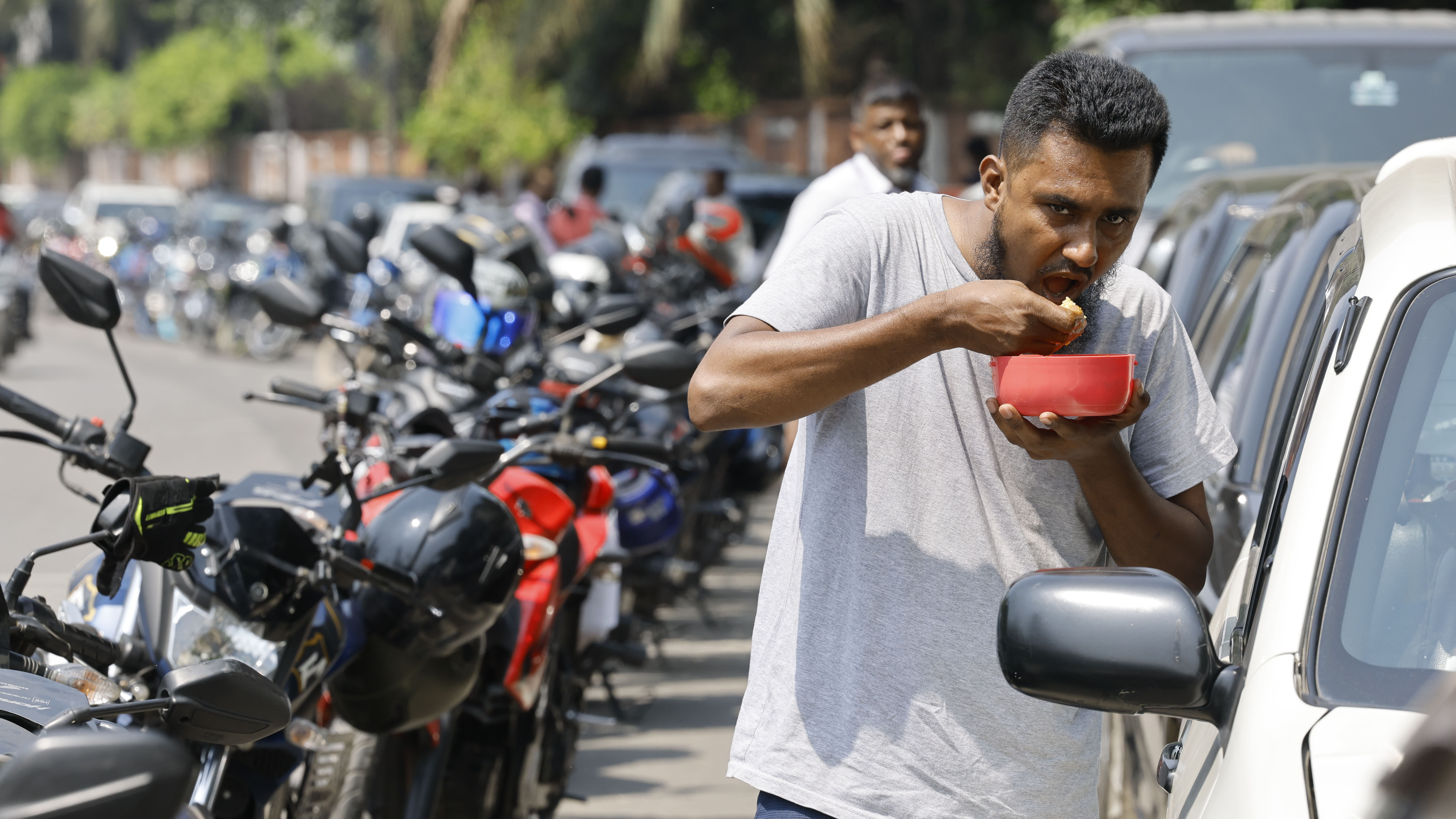 সকালে এসে দাঁড়িয়েছেন লাইনে, কখন তেল পাবেন ঠিক নেই। তাই রাস্তায় দুপুরের খাবার খাচ্ছেন একজন