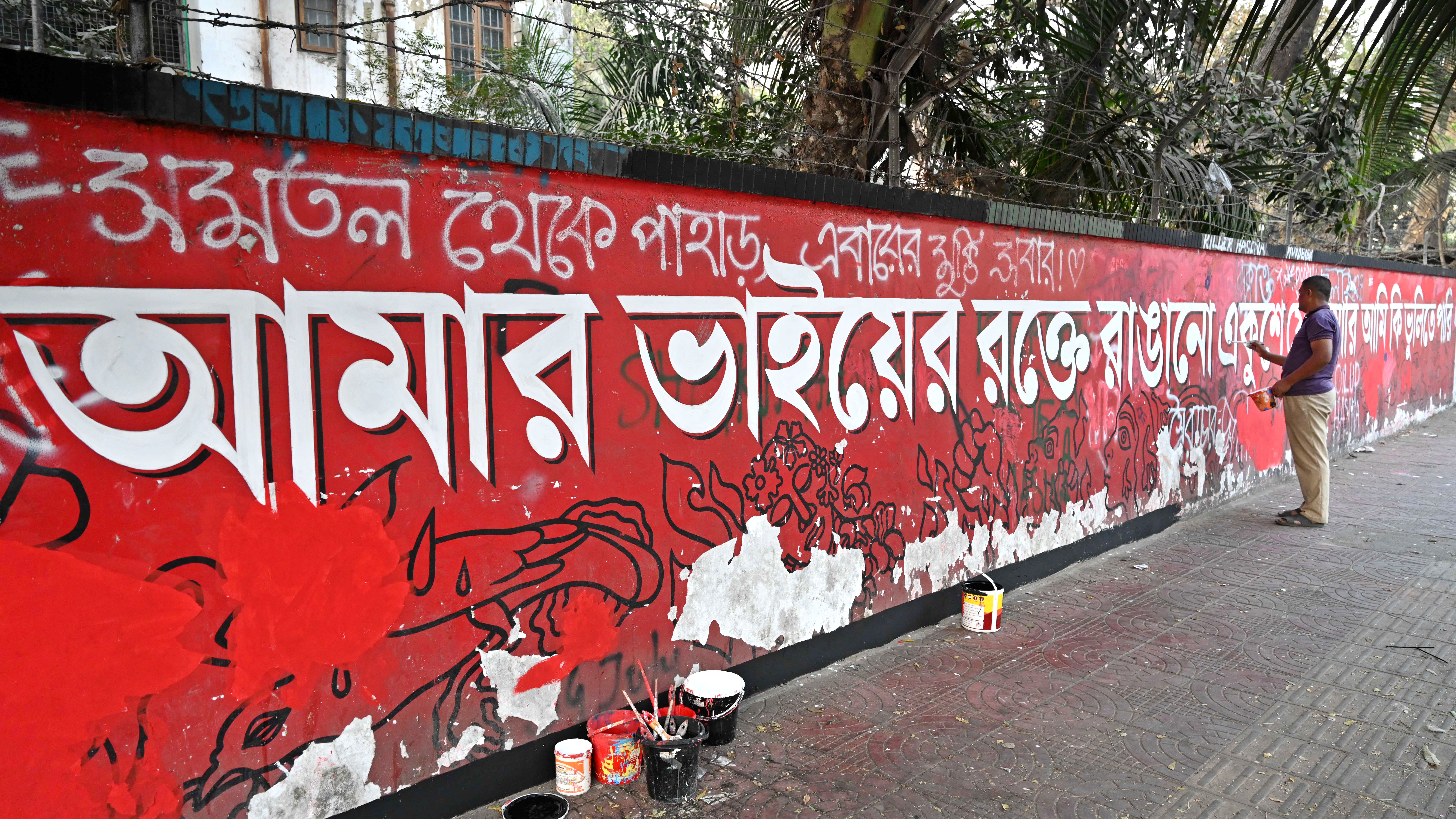 দেয়ালের পুরোনো লেখাকে নতুন রূপ দিতে ব্যস্ত এক শিক্ষার্থী