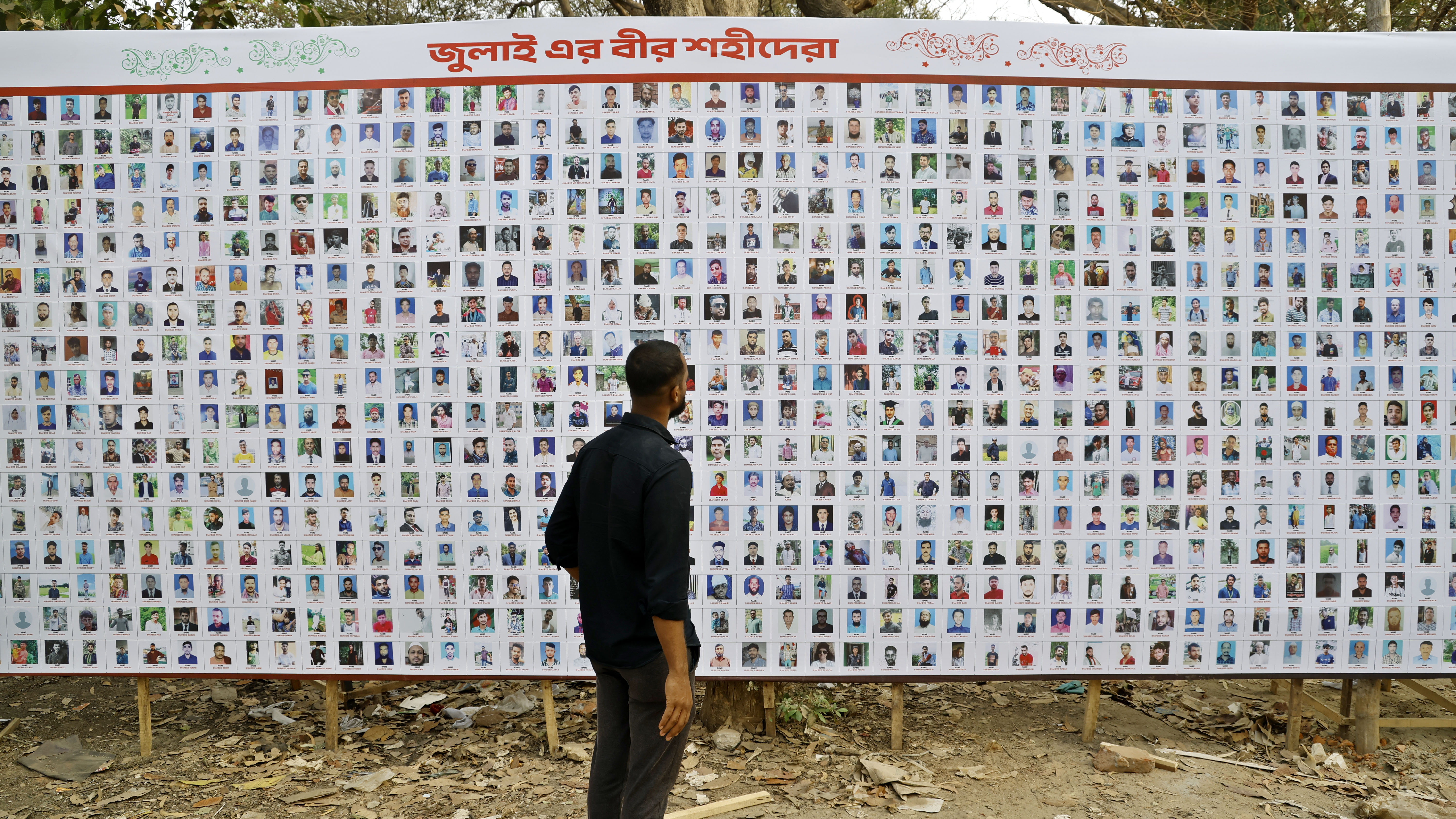 জুলাই ফাউন্ডেশনের স্টলের সামনে শহীদদের ছবি দেখছেন একজন