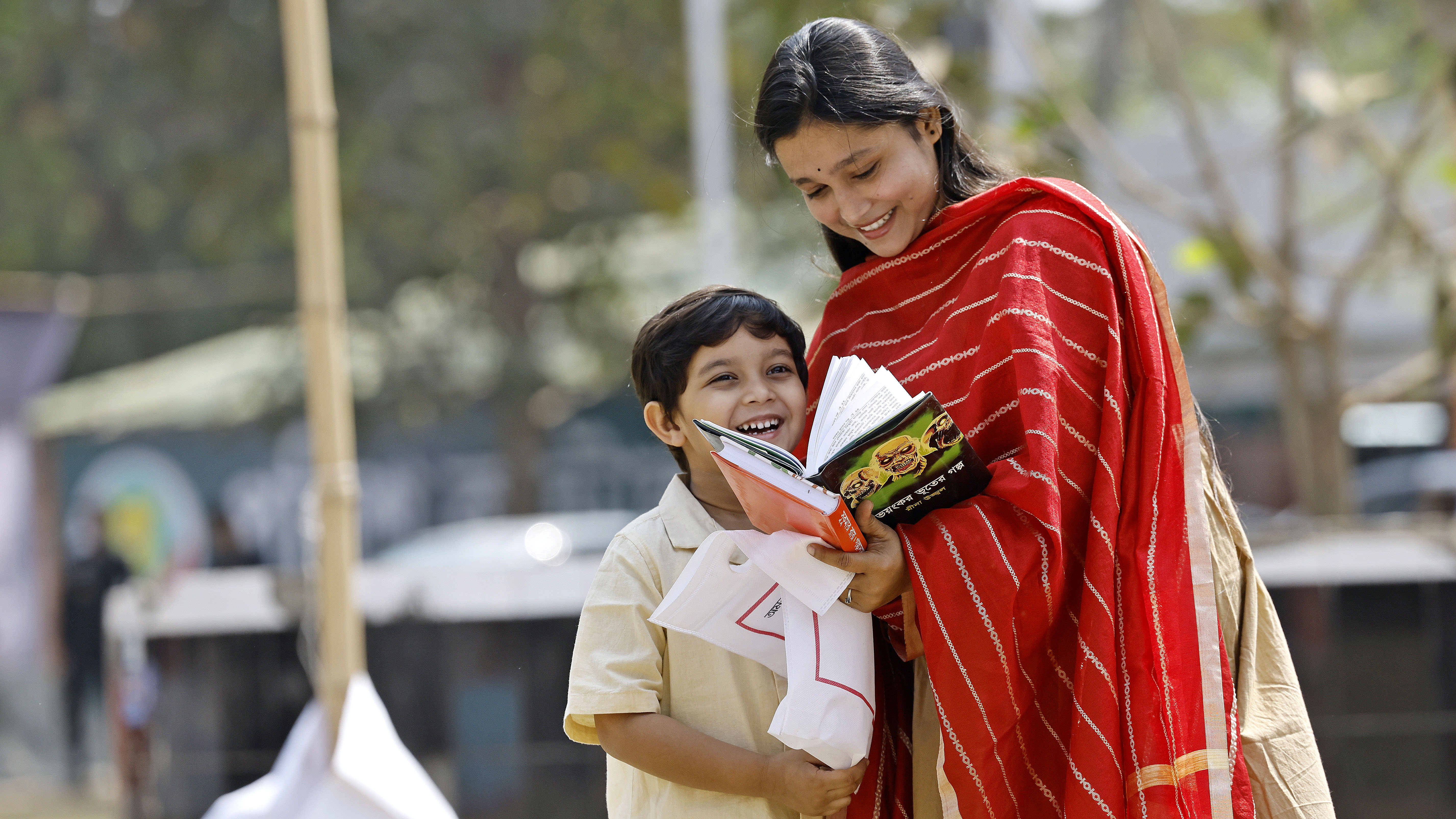 শিশুপ্রহরে বই মেলায় মায়ের সঙ্গে হাস্যোজ্জ্বল এক শিশু