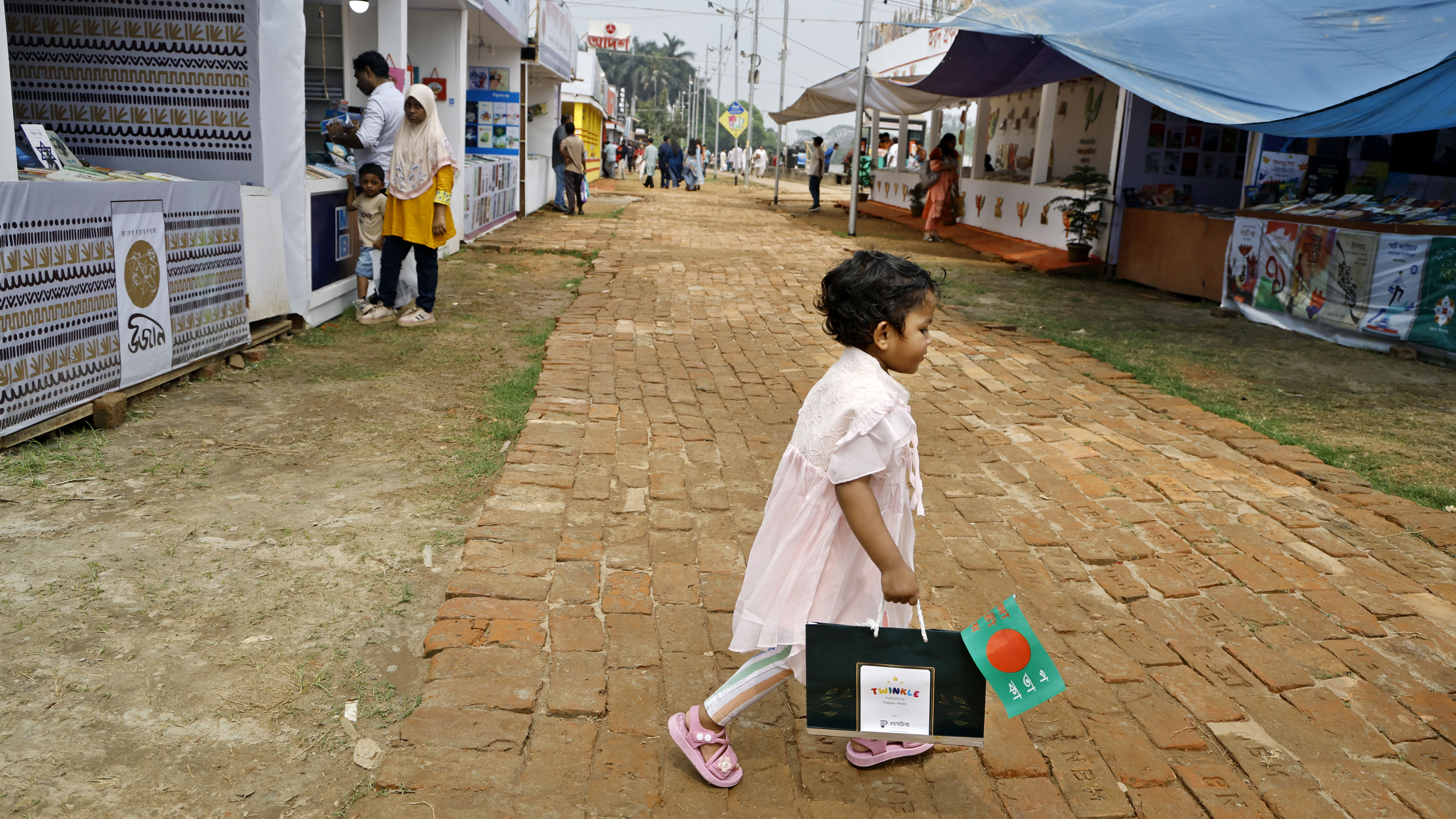 পছন্দের বই হাতে পেয়ে বাবাকে পেছনে ফেলে মেলা ঘুরে বেড়াচ্ছেন এক শিশু
