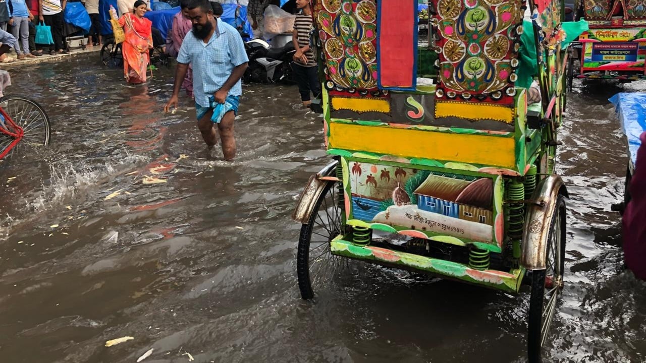 কর্মব্যস্ত দুপুরে হঠাৎ ঝুম বৃষ্টি এসে পানিতে ডুবিয়ে দিয়ে গেছে পথঘাট। নিউমার্কেটে কেনাকাটা করতে আসা অনেককেই তাই পথ চলতে হয়েছে এভাবে! ছবি: সিটিজেন জার্নাল