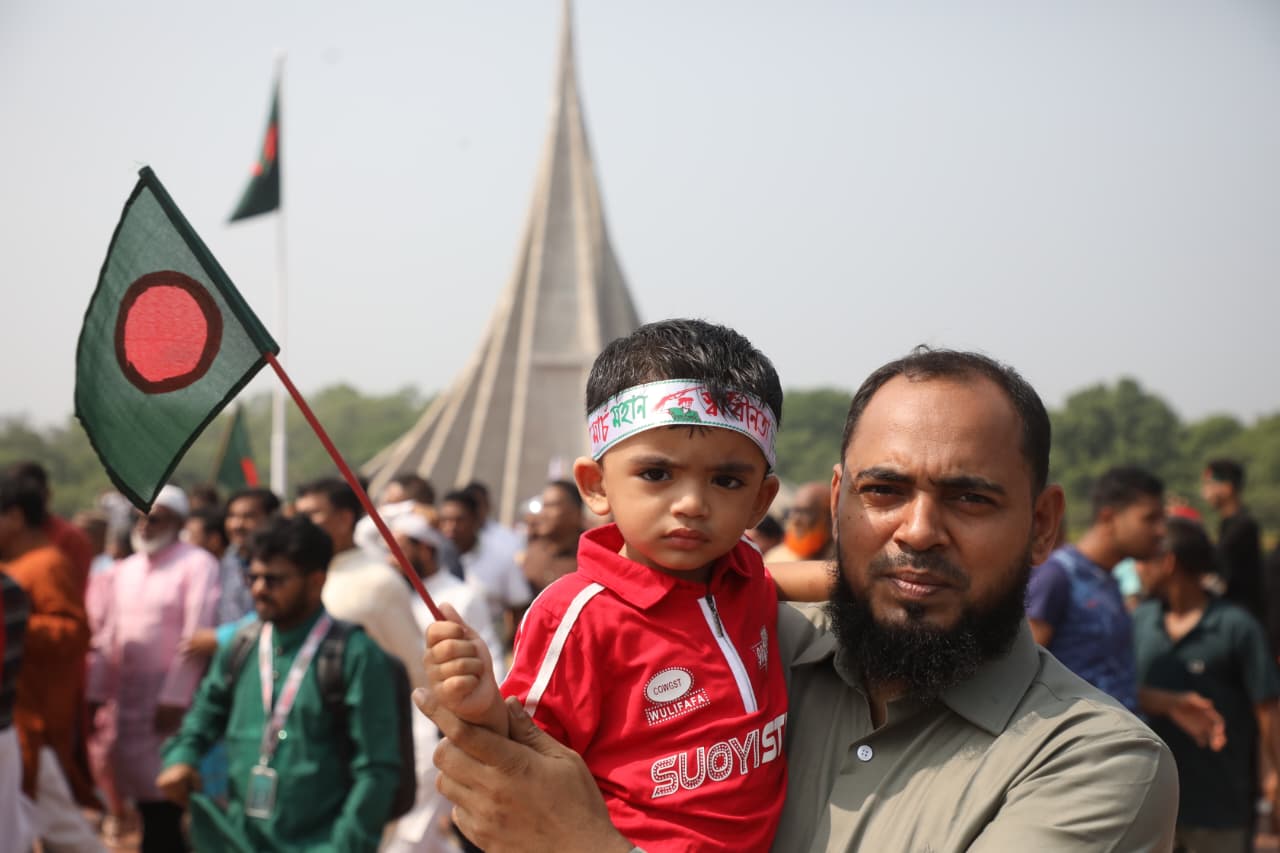 পিতার কোলে বাংলাদেশের পতাকা হাতে এক শিশু