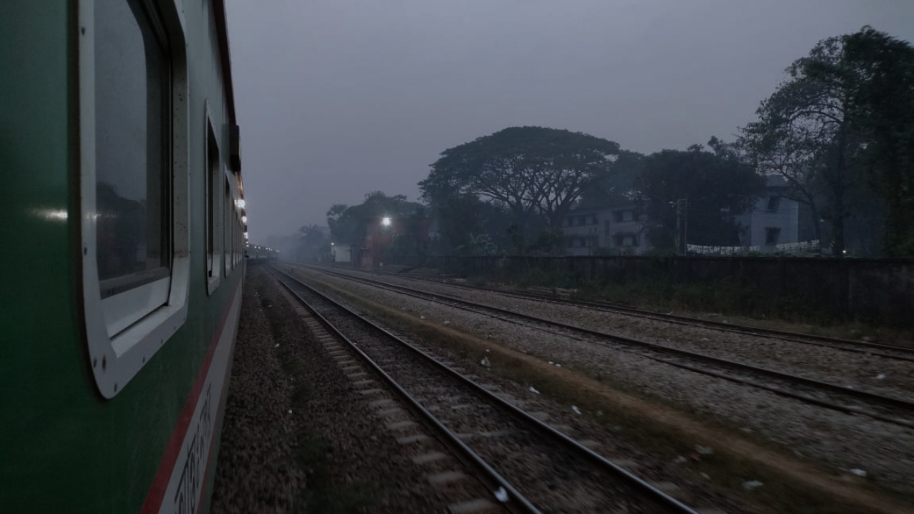 ঘন কুয়াশার বুক চিরে এগিয়ে চলা ট্রেন, শীতের সকালের নীরবতার মাঝে গতিময় জীবনের প্রতীক।